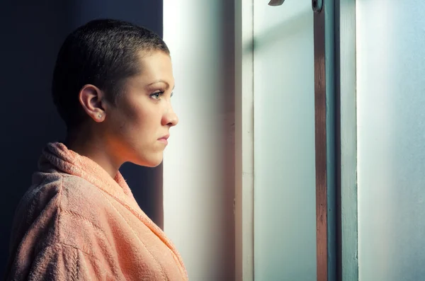 Unga deprimerade cancerpatient stående framför sjukhuset fönster — Stockfoto