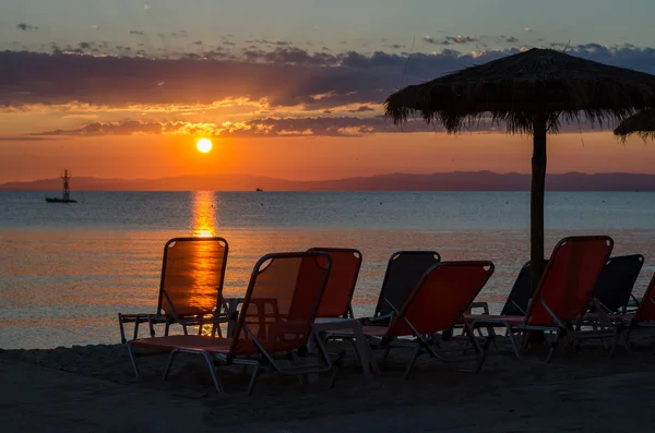 Lehátka a slunečníky na pláži u moře písku v létě sunrise — Stock fotografie