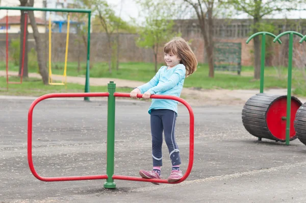 Glada leende liten flicka som leker på lekplatsen våren — Stockfoto