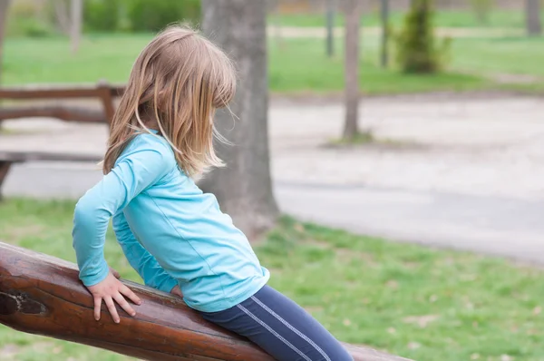 Menina triste brincando sozinha no playground ao ar livre — Fotografia de Stock