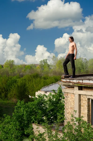 Mladí odvážné dobrodružství muž stojící na střešní hrany stará budova — Stock fotografie