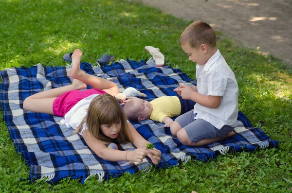 Older sister playing with two younger brothers on blanket — Stock Photo, Image