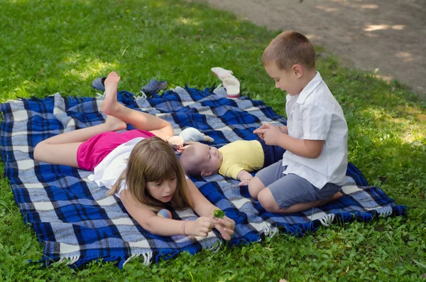 Sœur aînée jouant avec deux jeunes frères sur couverture — Photo