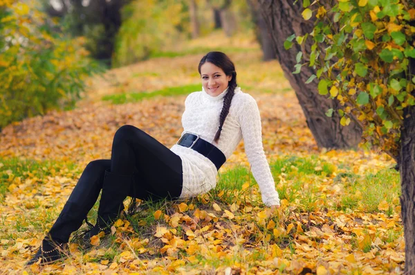Красива дівчина сидить на осінньому листі — стокове фото