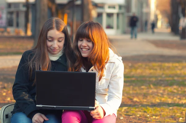 Zwei schöne Teenager-Mädchen haben Spaß mit Notizbuch im Park — Stockfoto