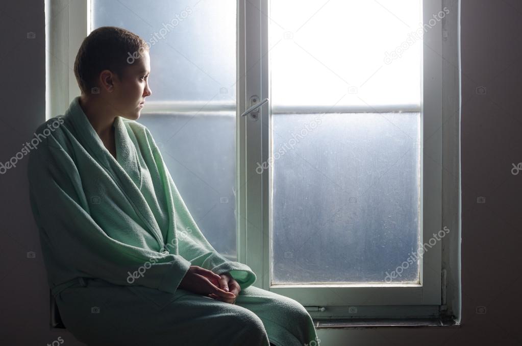 Young cancer patient sitting in front of hospital window