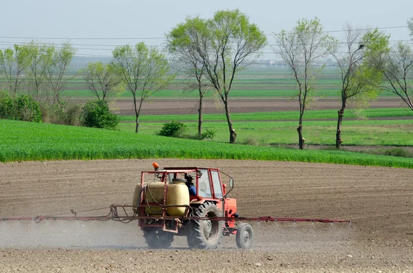 Traktor versprüht Pestizide gegen Käfer auf gepflügtem Land in der Sonne — Stockfoto