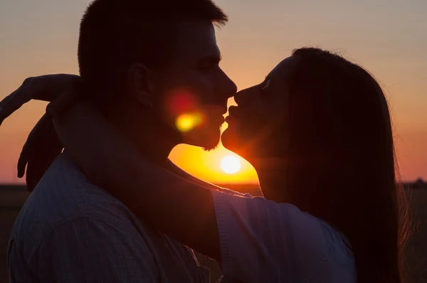 Silhouetten von sich küssenden Pärchen bei sommerlichem Sonnenuntergang — Stockfoto