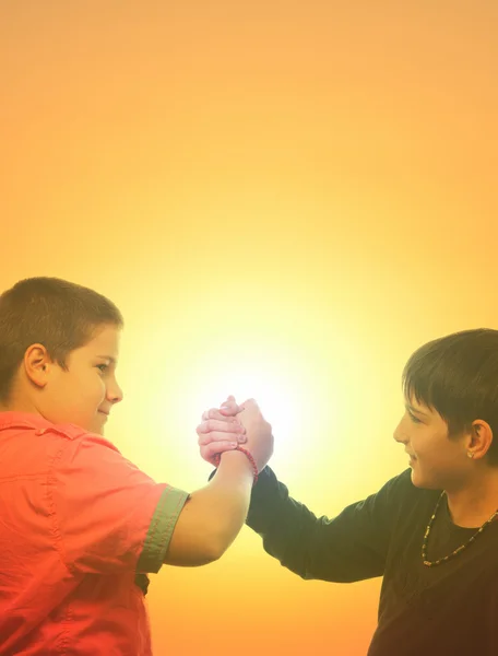 Twee tienerjongens hand schudden tegen zonnige hemel — Stockfoto