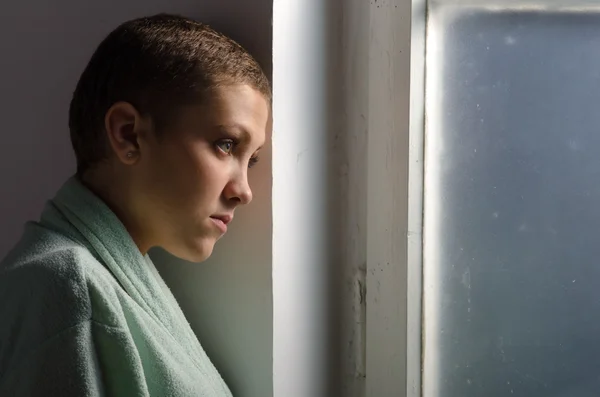 Junge Krebspatientin steht vor Krankenhausfenster — Stockfoto