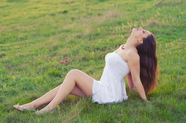 Gelukkig elegante vrouw zitten op de weide op prachtige lente da — Stockfoto