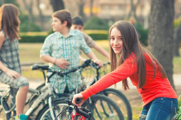 Nastolatka zabawy na rowery z przyjaciółmi w parku — Zdjęcie stockowe