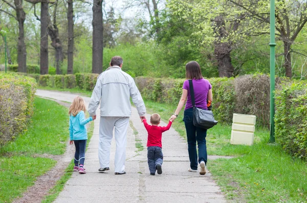 Junge Familie spaziert im Park an einem schönen bewölkten Frühlingstag — Stockfoto