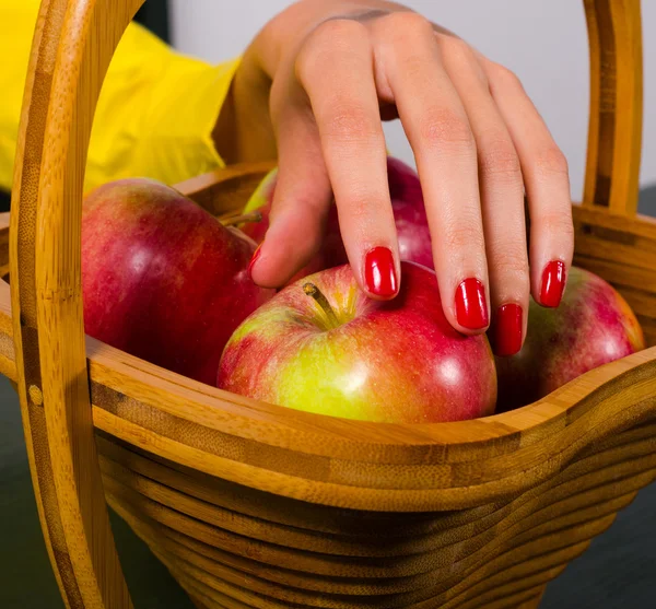 Elegante Frau pflückt Apfel aus Holzkorb — Stockfoto