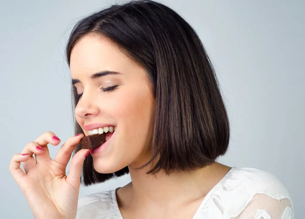 Retrato de la hermosa chica comiendo galletas de chocolate aisladas — Foto de Stock