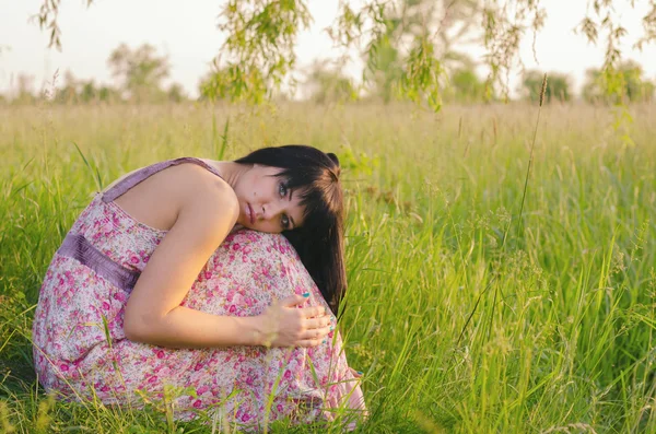 Çayır on güneşli yaz gününde yalnız oturan güzel hüzünlü kız — Stok fotoğraf