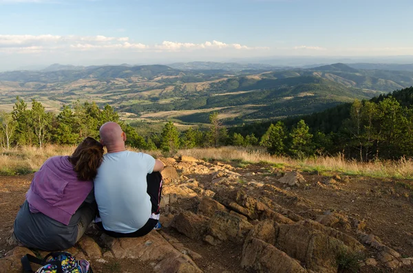 Pareja joven sentada en la cima de la montaña en verano soleado — Foto de Stock