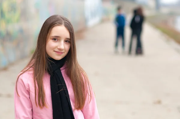 Pretty smiling girl on roller skates posing outdoor with friends — Stock Photo, Image