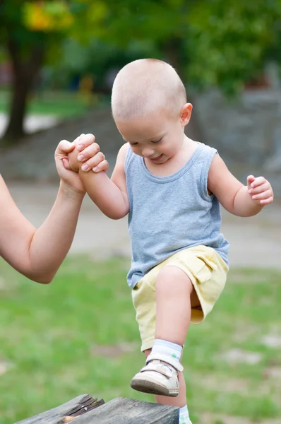 Liten glad pojke klättra upp i trä pelare på lekplatsen utomhus — Stockfoto