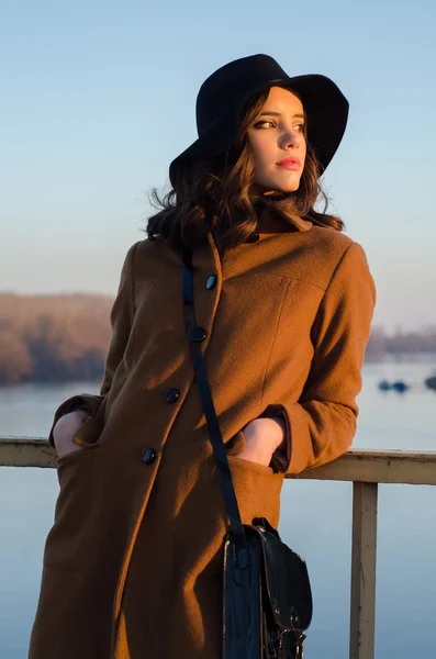 Belle jeune femme debout sur le pont regardant coucher de soleil d'automne sur le lac — Photo