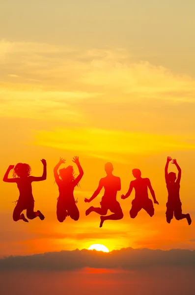 Teenage boys and girls jumping high in the air against colorful sunset — Stock Photo, Image