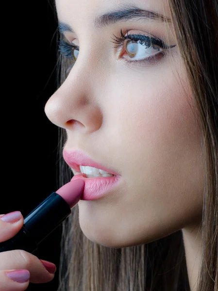 Porträt des schönen brünetten Mädchens, das rosa Lippenstift auf den Mund legt — Stockfoto