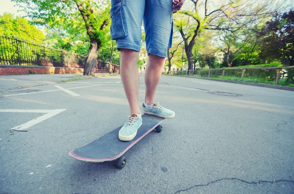 Teenagers legs and skateboard on road on summer day — Stock Photo, Image