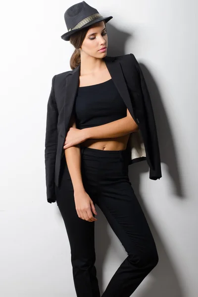 Menina elegante bonita em roupas pretas inclinando-se na parede branca — Fotografia de Stock