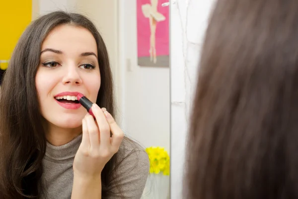 Hermosa chica poniendo lápiz labial delante del espejo —  Fotos de Stock