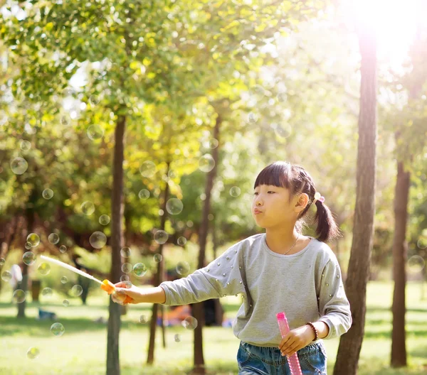 Girl blowing soap bubbles at park — Stock Photo, Image