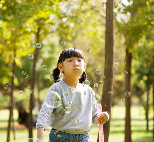 Girl blowing soap bubbles at park — Stock Photo, Image