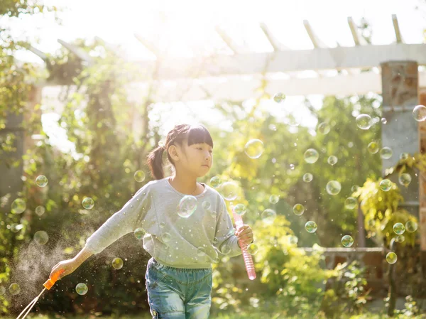 Girl blowing soap bubbles at park — Stock Photo, Image