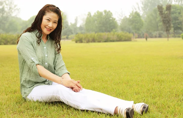 Elderly woman sitting outside the lawn — Stock Photo, Image