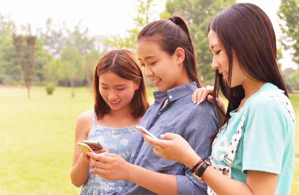 Tre studenter med mobiltelefon — Stockfoto