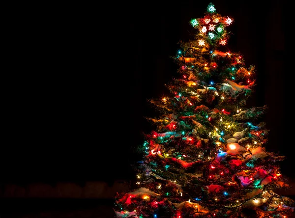 Çok renkli ışıklar ile Noel ağacı kar kaplı