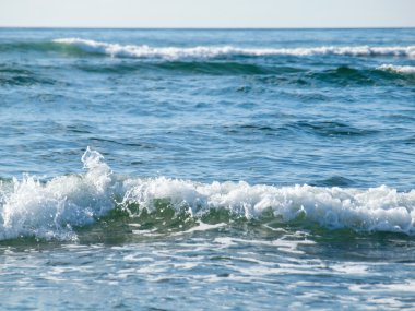 Okyanus dalgaları sahilde bulutsuz bir günde kırma