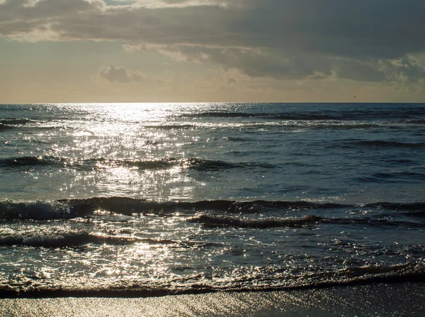 Ondas do oceano quebrando na praia como o sol está indo para baixo — Fotografia de Stock