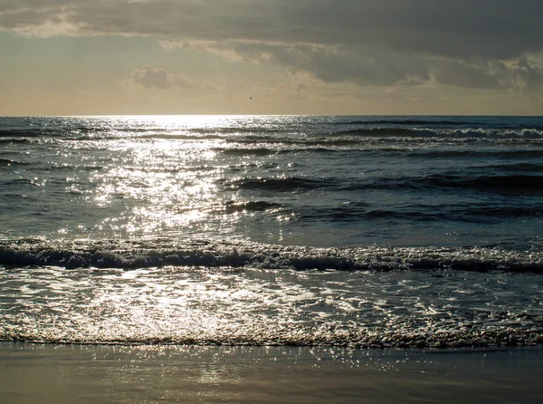 Ondas do oceano quebrando na praia como o sol está indo para baixo — Fotografia de Stock