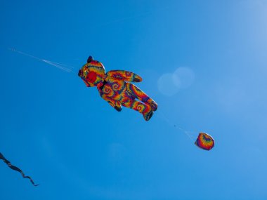 Renkli kravat boya ayı Bulutsuz mavi gökyüzünde uçan uçurtma