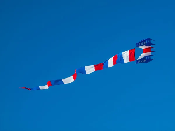 Pipa vermelha, branca e azul voando no céu azul sem nuvens — Fotografia de Stock