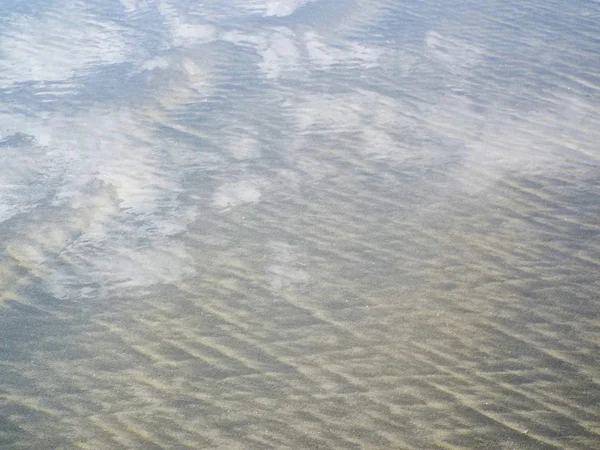 Himmel und Wolken spiegeln sich im Wasser am Ufer — Stockfoto