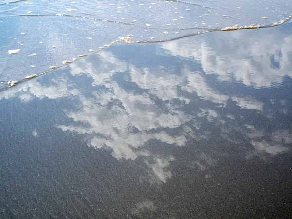 Himmel und Wolken spiegeln sich im Wasser am Ufer — Stockfoto