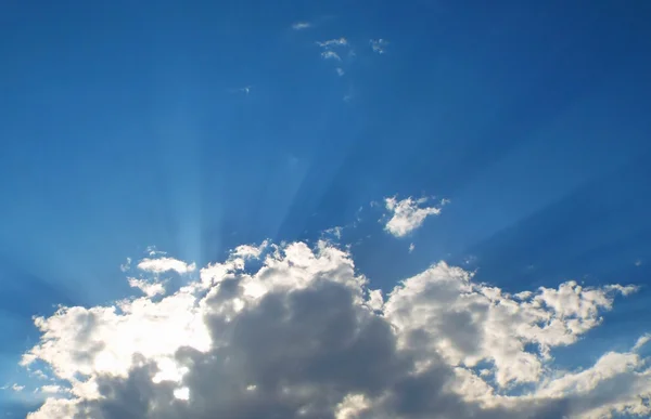 Raios de sol brilhando por trás de nuvens cinzentas e brancas — Fotografia de Stock