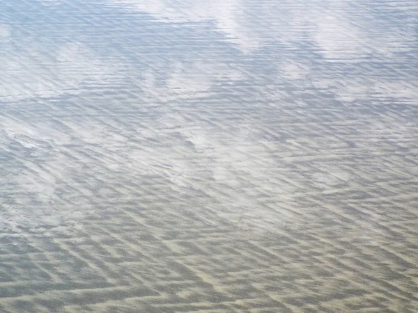 Himmel och moln reflektioner i vattnet vid stranden — Stockfoto