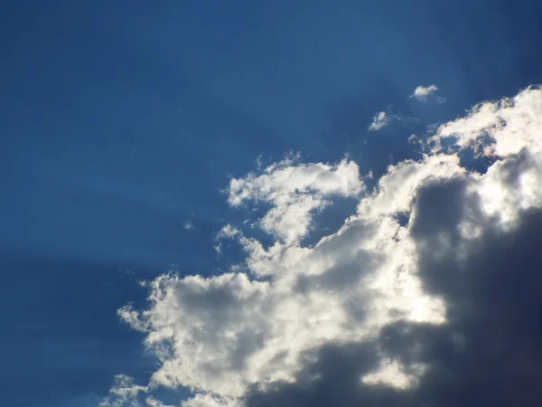 De stralen van de zon schijnt achter de grijze en witte wolken — Stockfoto