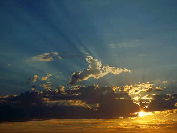 Облачный закат над океаном с солнечными лучами в небе — стоковое фото