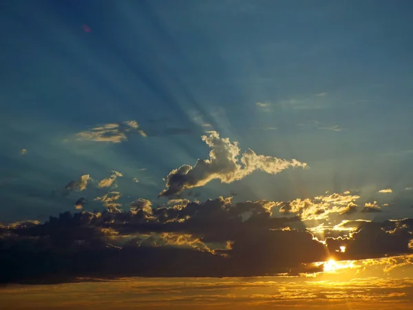 Wolkenverhangener Sonnenuntergang über dem Meer mit Sonnenstrahlen am Himmel — Stockfoto