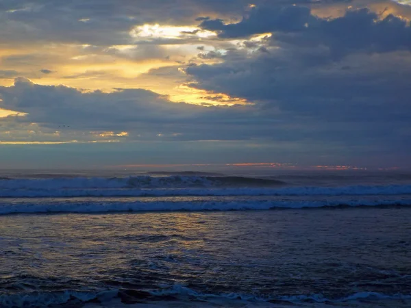 Okyanus dalgaları ön planda ile bulutlu gün batımı — Stok fotoğraf