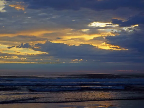 Bewolkt zonsondergang Over de oceaan met golven op de voorgrond — Stockfoto