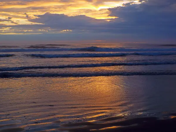 Tramonto nuvoloso sull'oceano con onde in primo piano — Foto Stock